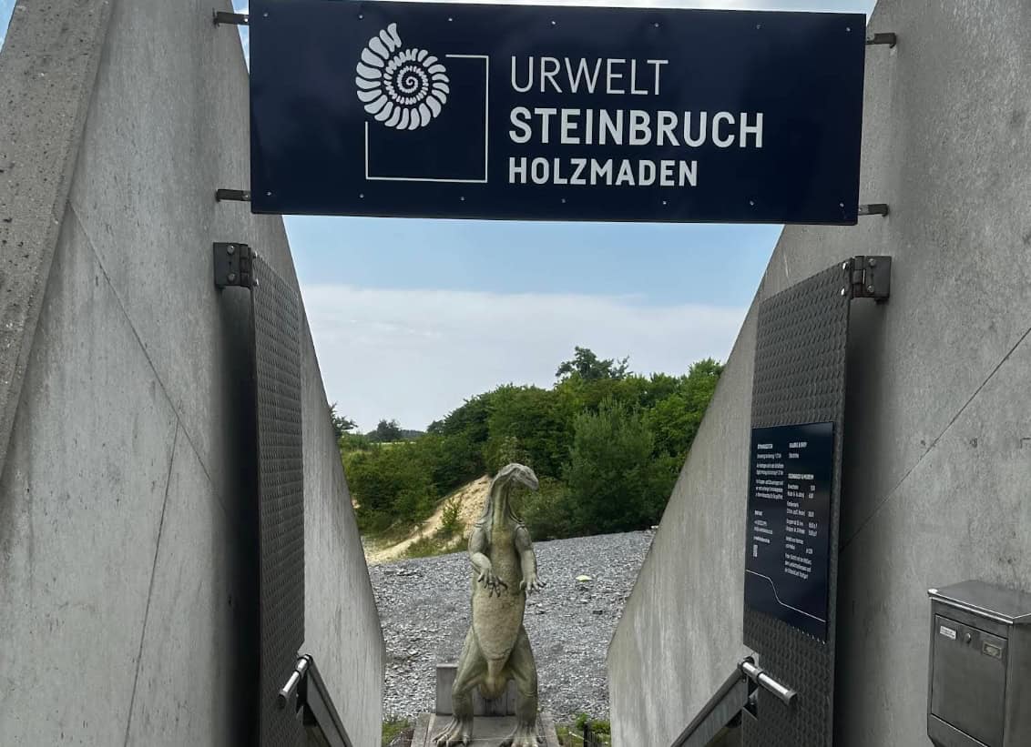Moderner Eingang des Urweltsteinbruchs Holzmaden mit Schild und Dinosaurier-Skulptur