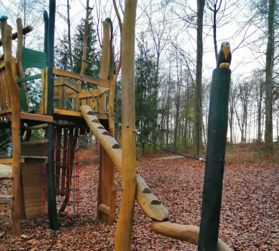Holz-Spielgerüst im Wald mit Rutsche und Kletterelementen